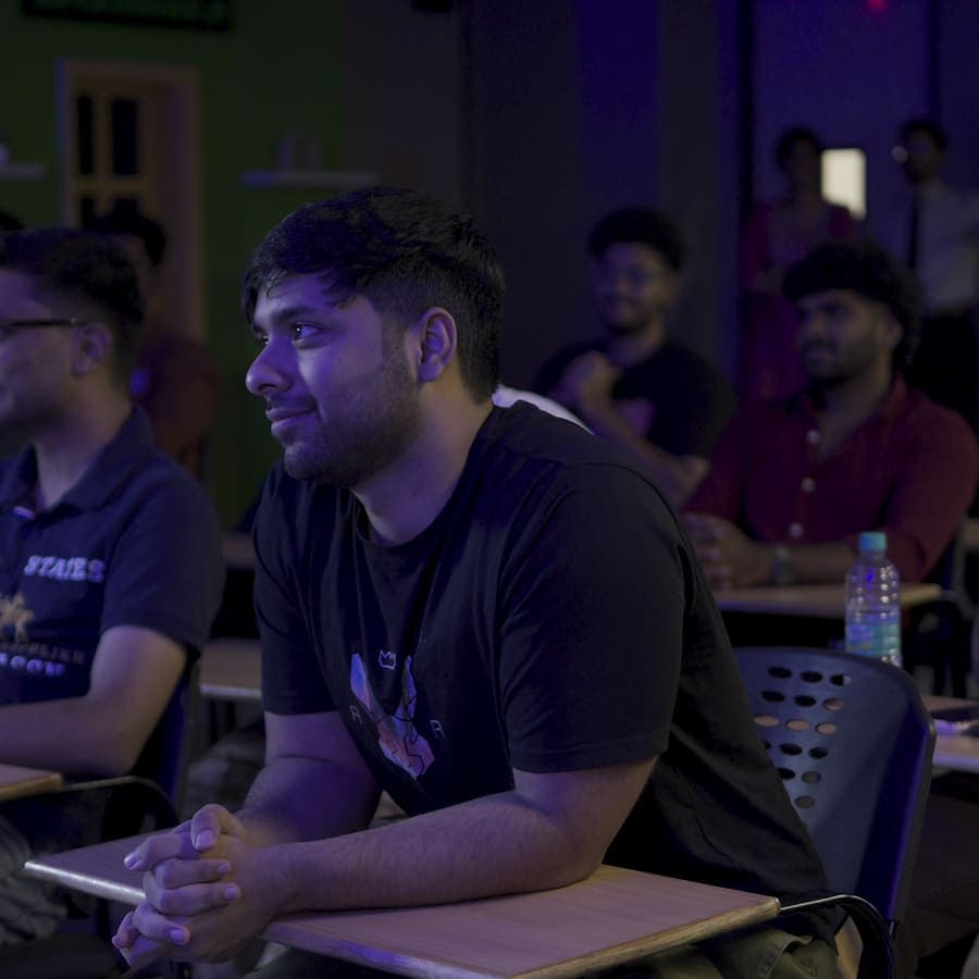 A GenC student smiling as he writes during a class